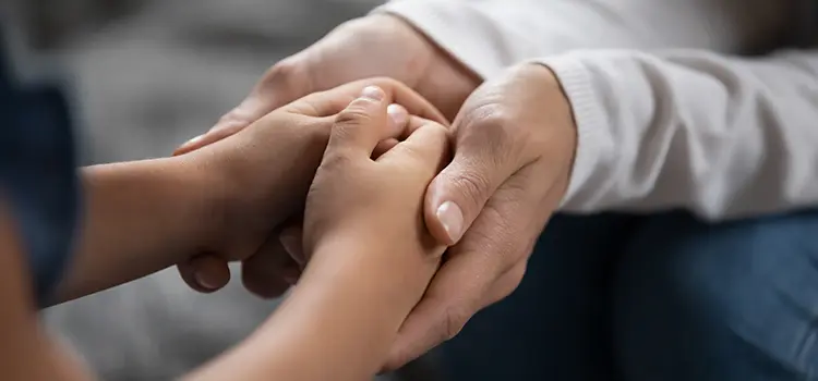 A parent holding a child's hands.