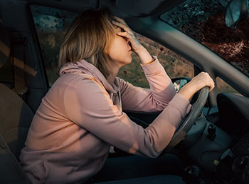 A photo of a women holding her face behind the steering wheel after an accident.