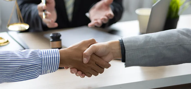 A photo of two individuals shaking hands in front of a lawyer.