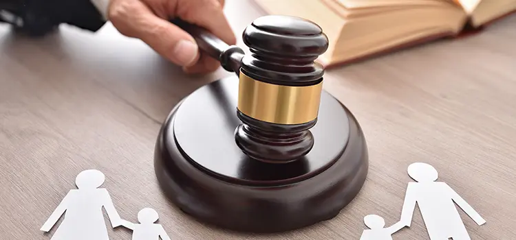 A photo of a judge striking their gavel on the table with paper cutouts of a family around the gavel.
