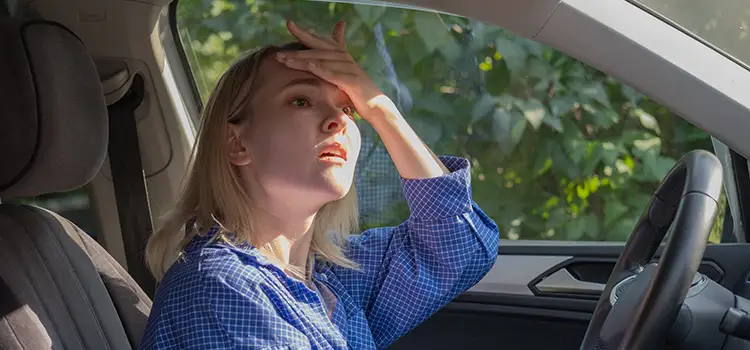 A photo of a woman in the driver's seat with her hand on her forehead with a look of dismay.